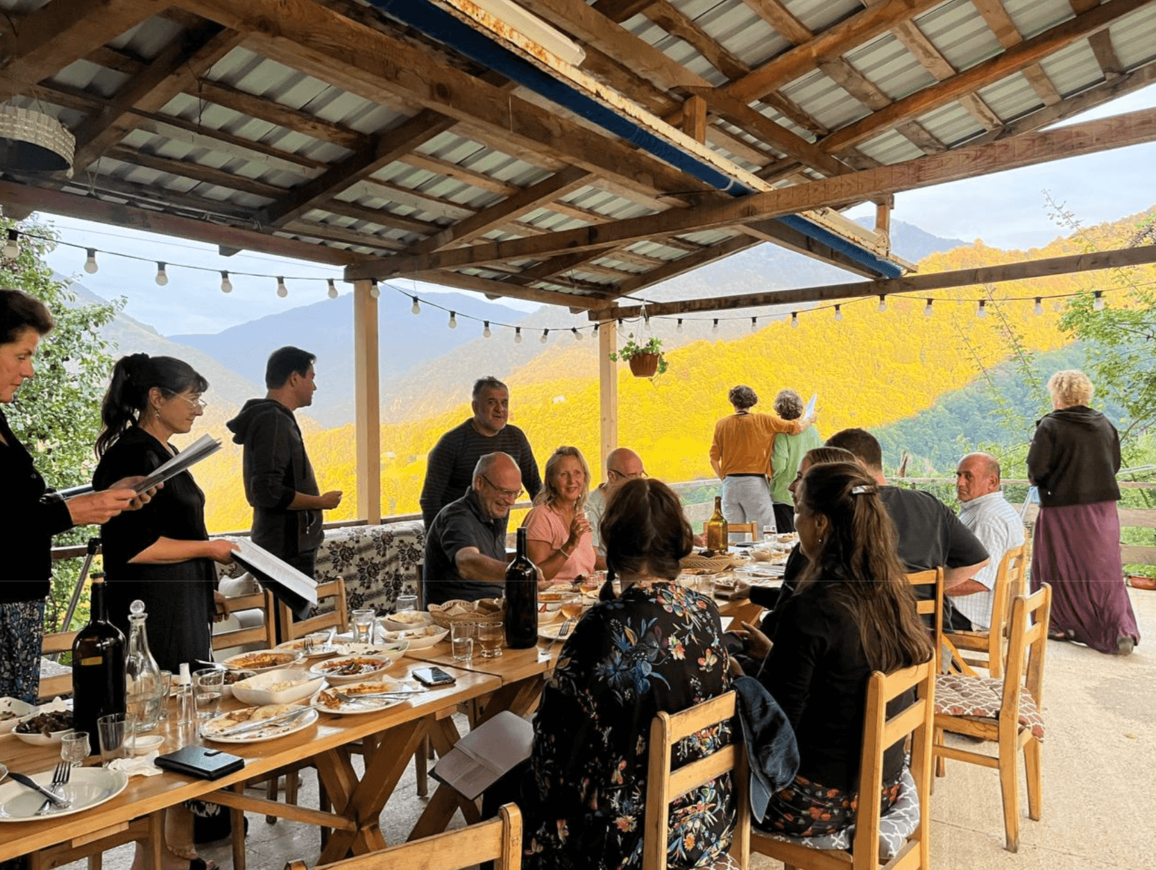 Люди за столом на фоне гор