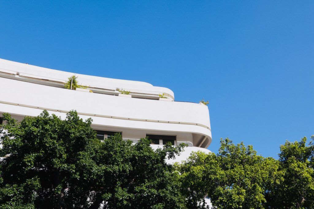 Белый дом на фоне голубого неба и зелёных деревьев