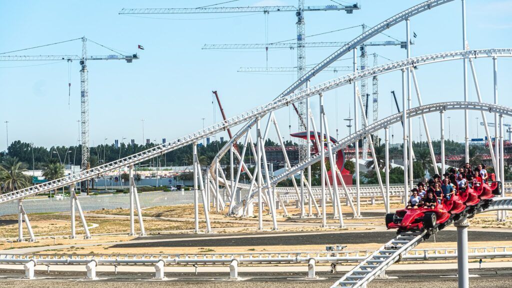 Американские горки на фоне песка и подъёмных кранов