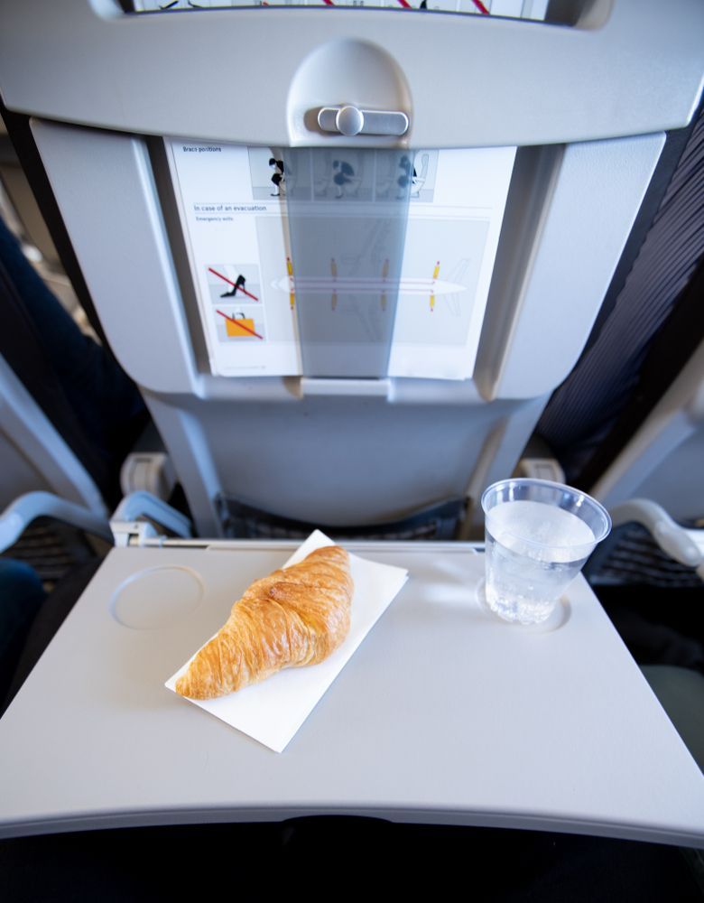 Круассан и вода на столике в самолёте
